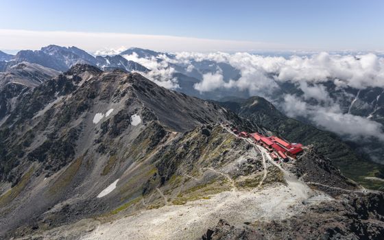 A breathtaking view of Japanese mountains with red-roofed shelters and cloudy skies.
