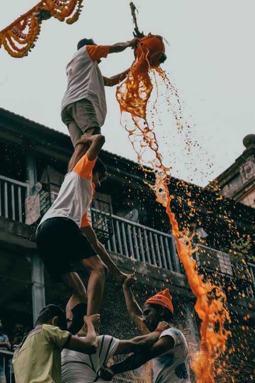 Free Dynamic scene of festival celebration with people pouring orange liquid from above. Stock Photo