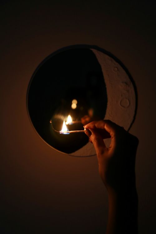 Free A hand delicately holds a burning match in front of a shadowed mirror, creating a mystical atmosphere. Stock Photo