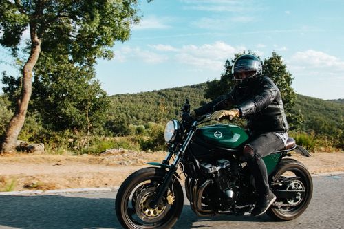 Free A biker wearing a helmet riding a motorcycle on a scenic rural road during a sunny day. Stock Photo