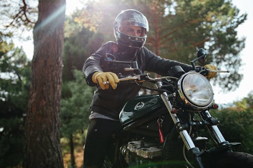 A Man in Black Leather Jacket Riding a Black Motorcycle