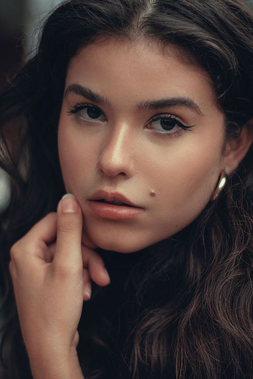Free Beautiful portrait of a woman with a beauty mark, exuding elegance and thoughtfulness. Stock Photo