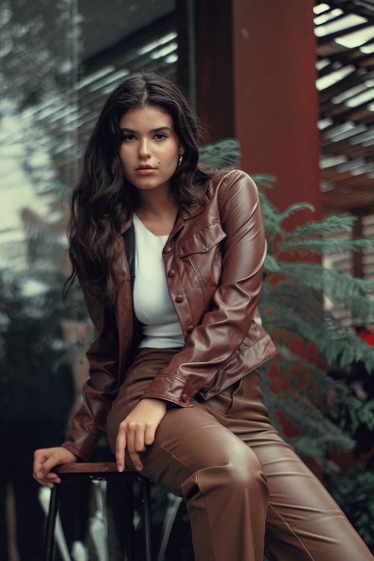 Woman In Leather Jacket And Pants Sitting On Stool