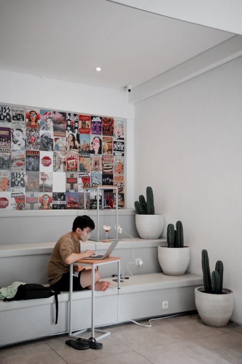 Free Adult male working on laptop in a modern indoor space, reflecting pandemic lifestyle with face mask and social distancing. Stock Photo