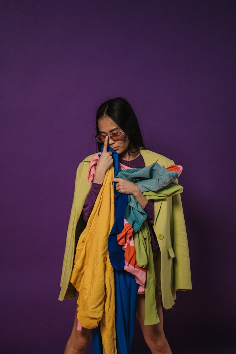 A Woman Wearing Sunglasses While Holding A Colorful Clothes