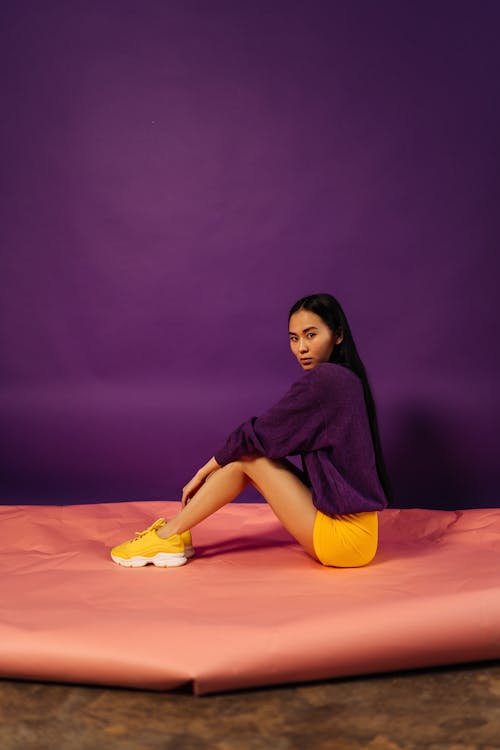 Free Young Woman with Long Black Hair Sitting on Big Sheet of Pink Paper Stock Photo