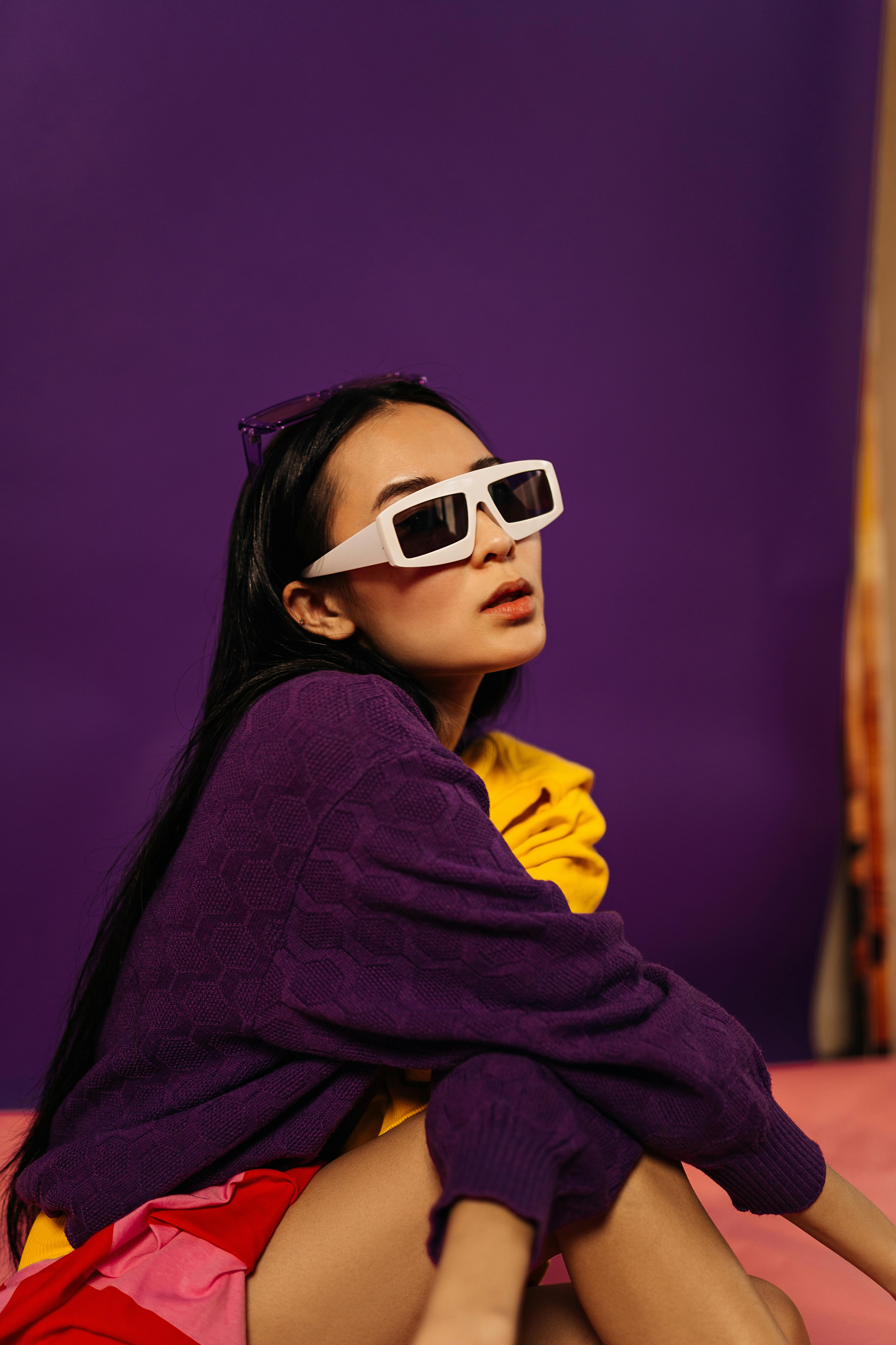 woman with long black hair in sunglasses sitting on floor