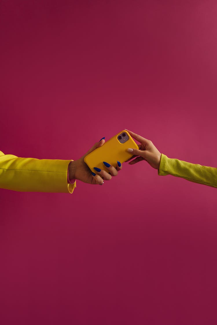 Two Unrecognizable Female Hands Holding Yellow Mobile Phone