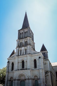 一座历史悠久的法国大教堂矗立在清澈的蓝天下，其经典建筑上复杂的石雕清晰可见