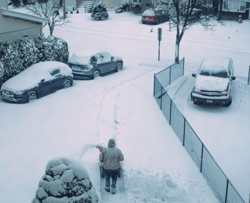 Person shoveling snow from a residential driveway after a fresh winter snowfall