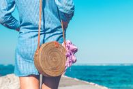 Woman Wearing Blue and White Striped Dress With Brown Rattan Crossbody Bag Near Ocean