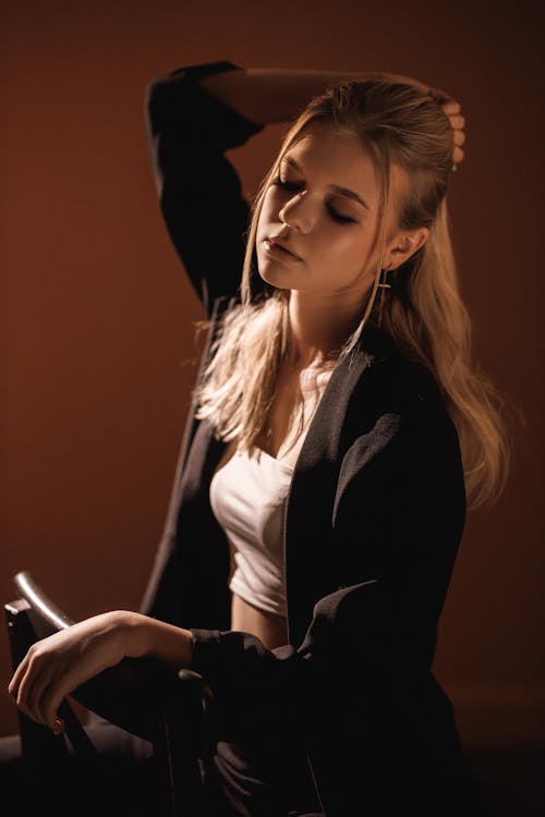 Free Young Blond Woman Sitting on Chair with Her Hand on Head Stock Photo