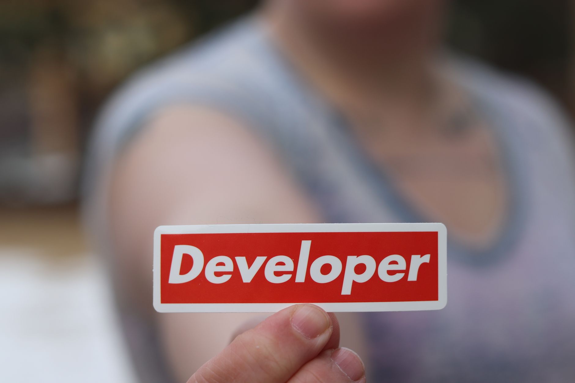 Une prise de vue en gros plan d'une main tenant une étiquette rouge avec le mot 'Développeur' en focus.