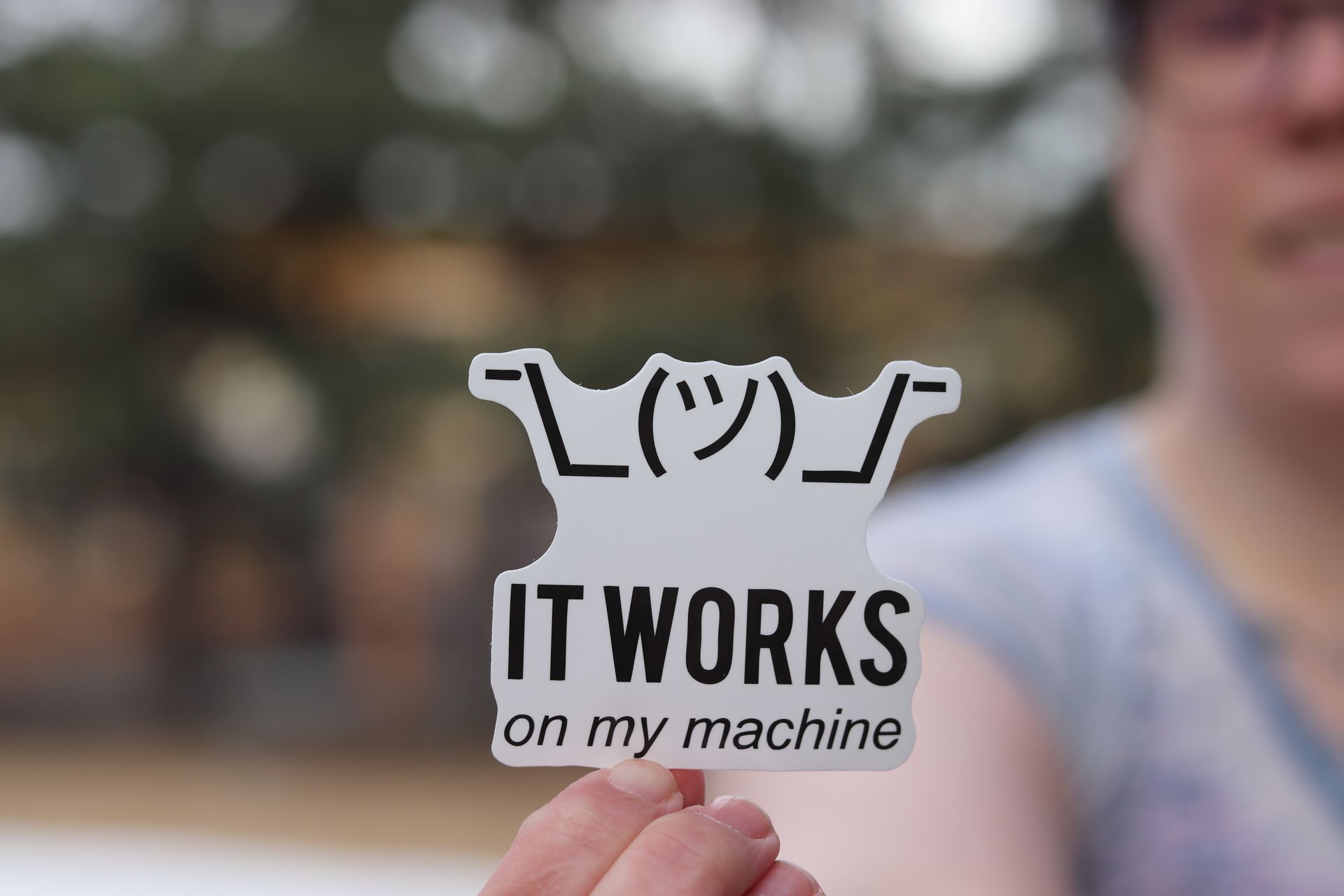 Person holding a humorous IT sticker outdoors, perfect for tech enthusiasts.