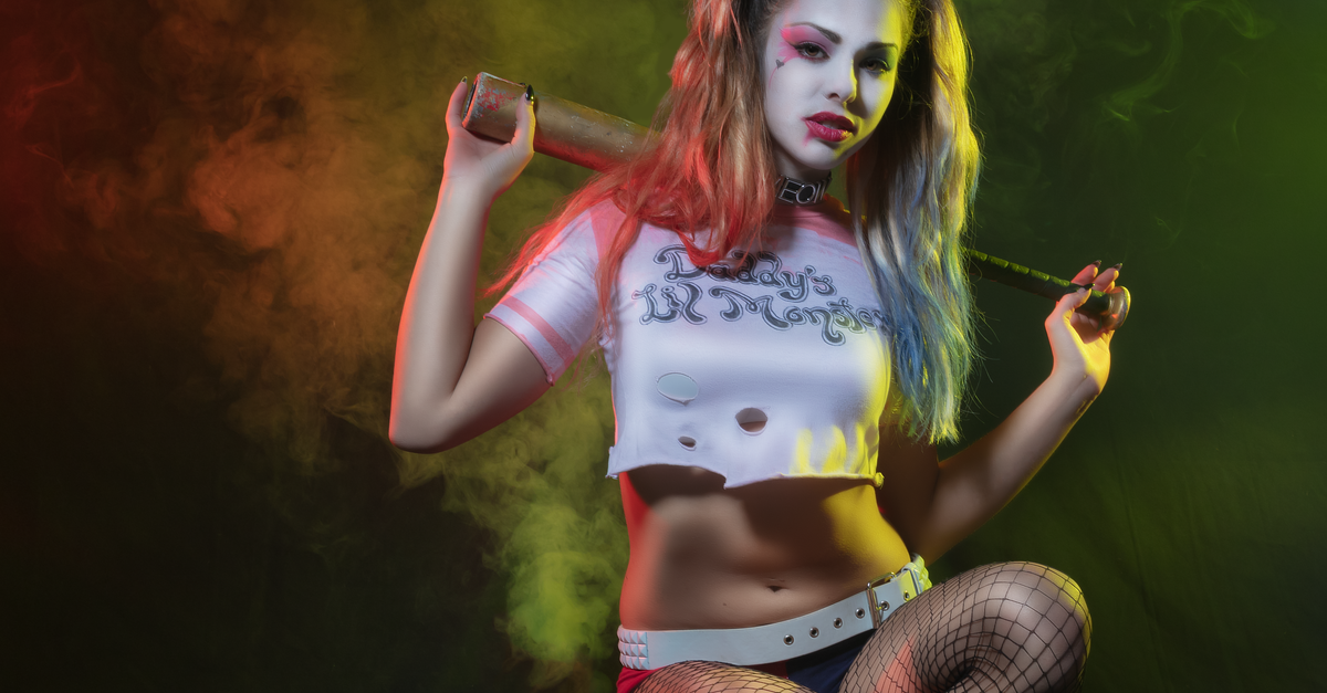 Rüyada Margot Robbie ile Harley Quinn Makyajı Yapmak - Rüya Tabiri ve Anlamı - Stylized Harley Quinn cosplay photoshoot with colorful smoke effects in a dark studio setting.