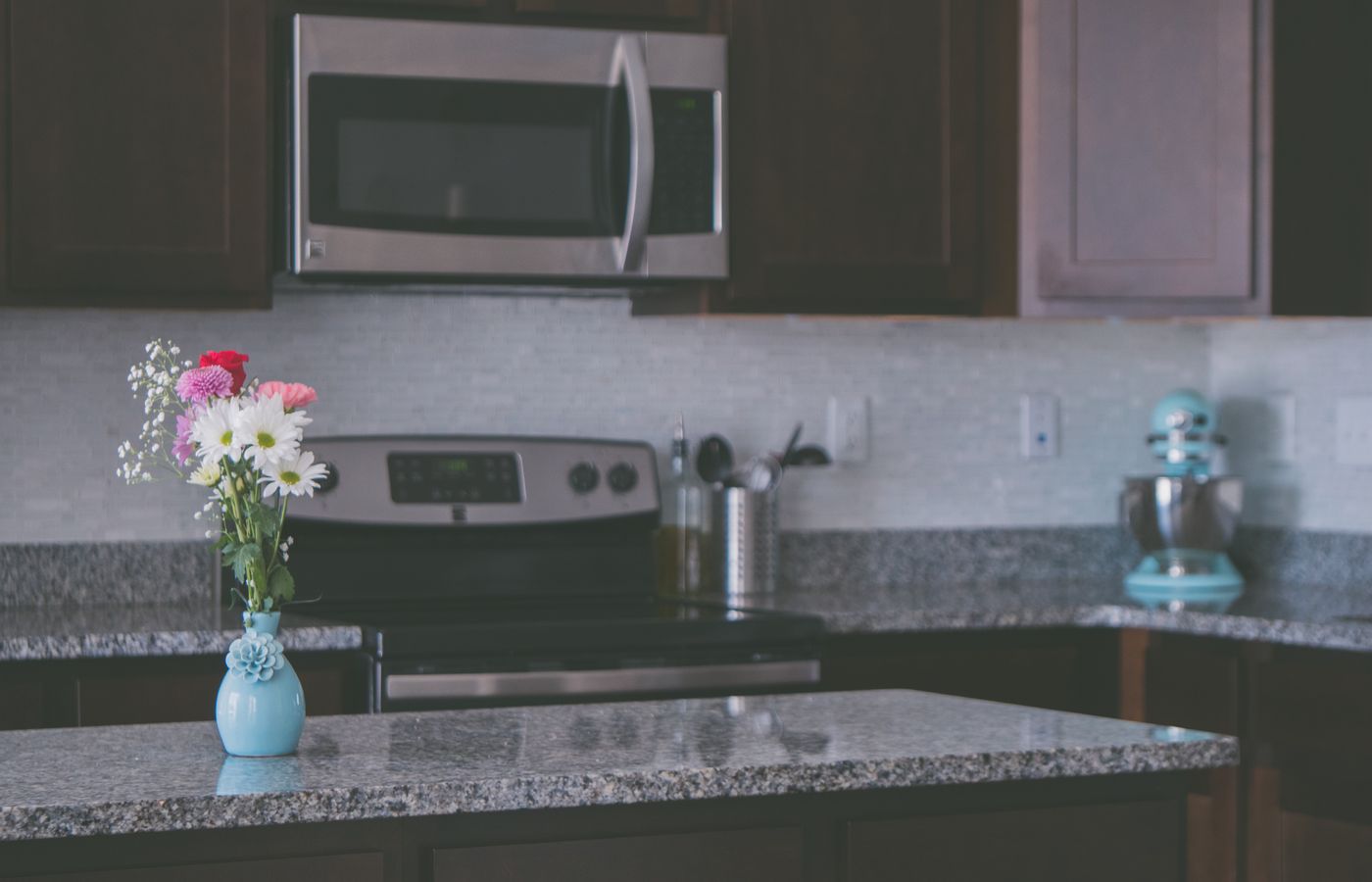 A contemporary kitchen featuring granite countertops and a vase of colorful flowers, creating a warm ambiance.
