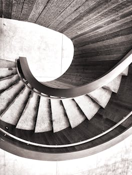 一张现代螺旋楼梯的单色图像，配有木制台阶和时尚设计