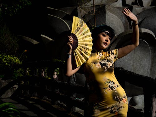 A Woman in Yellow Floral Dress Holding a Hand Fan