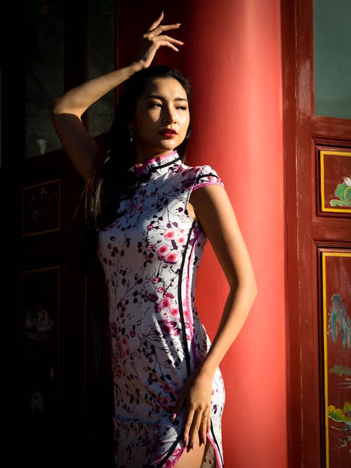 Young Woman Posing in Chinese Dress Leaning Against a Concrete Wall of a Temple

