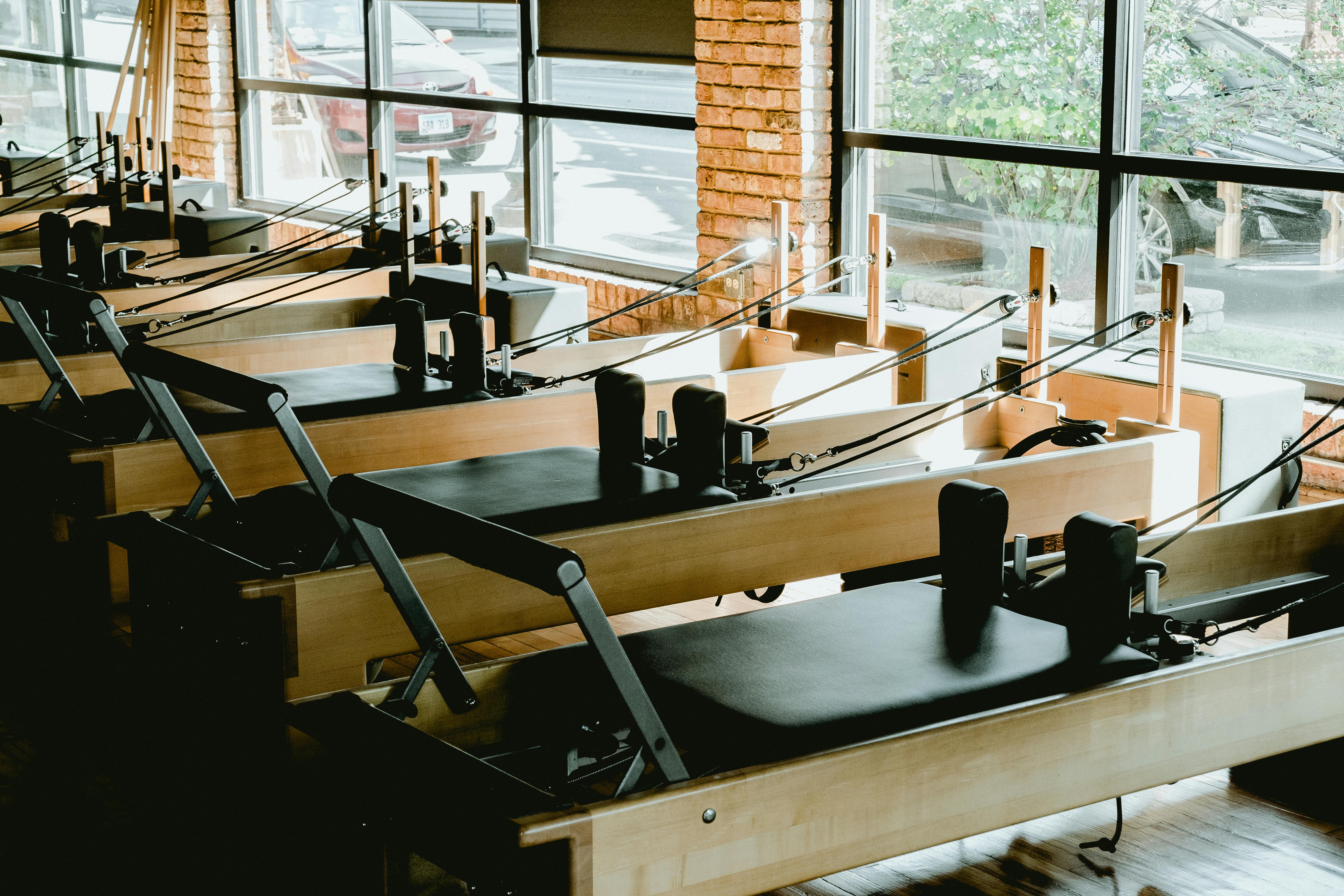 A bright, sunlit Pilates studio with Reformer machines and mats - early morning pilates classes near me