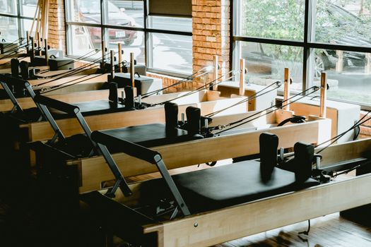 Bright pilates studio featuring multiple reformer machines by large windows.