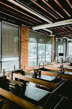 Spacious pilates studio featuring reformer equipment and large windows for ample natural light.