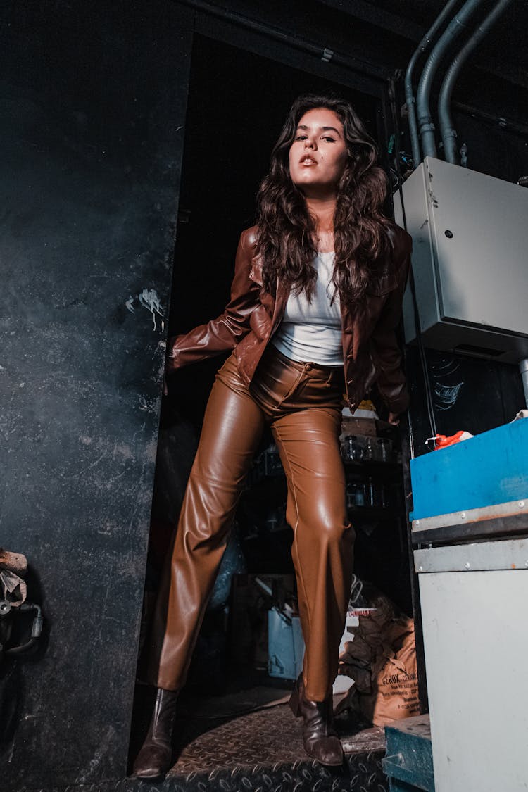 Woman In Leather Clothes In Corner Of Warehouse