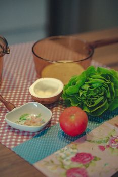 Close-up of fresh lettuce, tomato, and coconut with kitchenware on a rustic table.