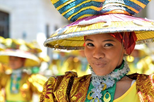 Smiling performer in colorful traditional attire at a Filipino festival.
