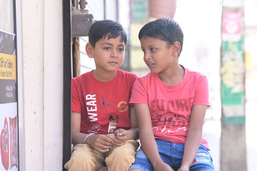 Two young boys in red shirts sitting together outdoors sharing a moment.