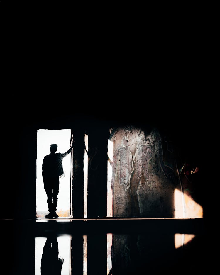 Silhouette Of Man Standing On The Doorway