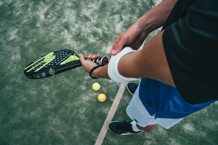 Person Holding Black And Green Tennis Racket