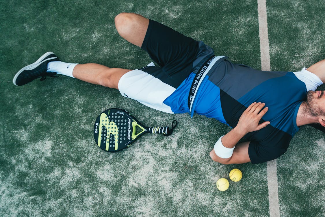 男子躺在綠色的網球旁邊