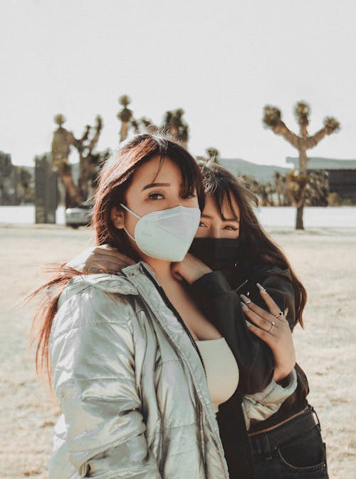 Free Women Embracing Together while Wearing Face Mask Stock Photo