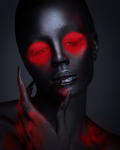 Black Painted Female Face with Red Creative Diabolic Makeup and Manicure