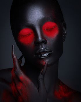 Dramatic portrait of a woman with bold red makeup on a black background.