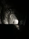 Grayscale Photo of Tunnel With Light