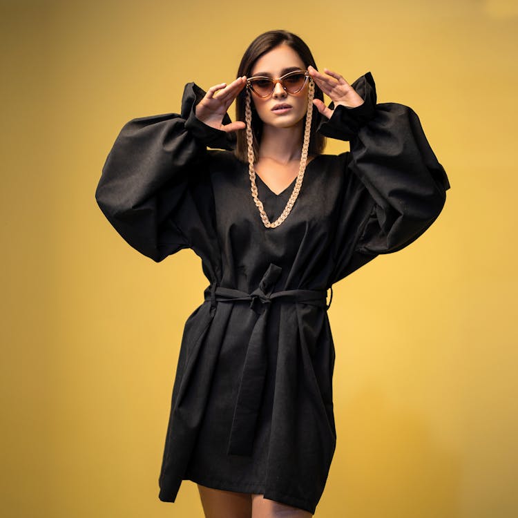 Woman In Black Dress Wearing Sunglasses On Gold Chain