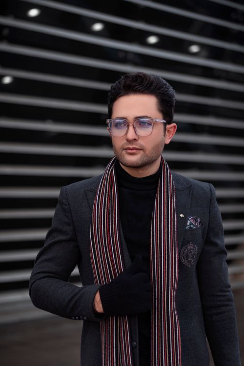 Free Portrait of a fashionable man wearing eyeglasses, suit, and scarf in an urban setting. Stock Photo