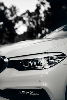 Detailed monochrome image showcasing a luxury car headlight with a sleek and modern design.