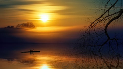 Человек катается на лодке во время заката
