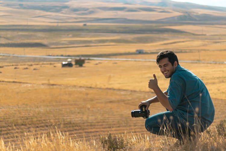 Man Squatting On Hill Top