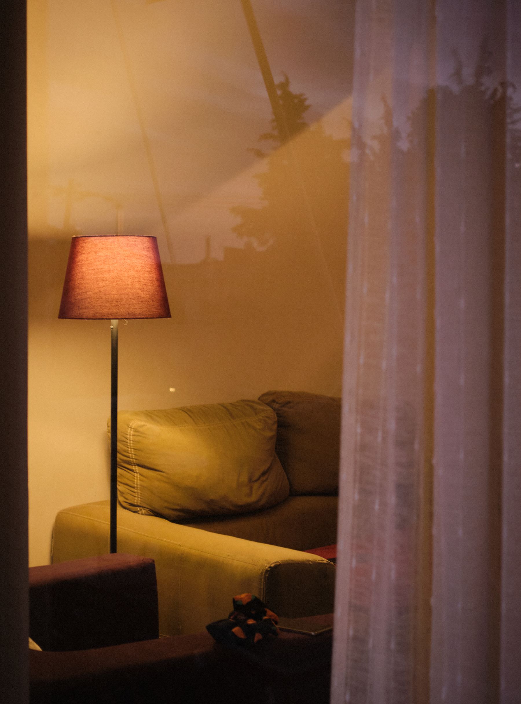 Warm floor lamp creating a soft evening atmosphere behind sheer curtains