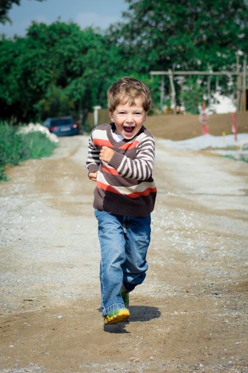 男孩穿著紅色，棕色和白色的條紋毛衣跑步照片