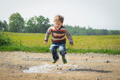 Kostenlos Junge, Der Tagsüber Nahe Gras Springt Stock-Foto