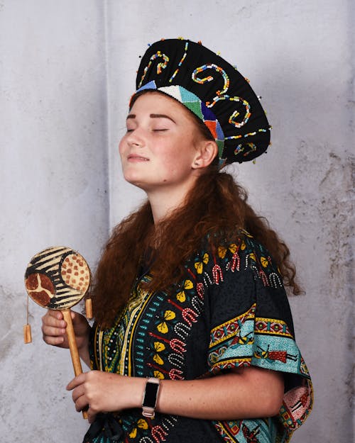 Woman in Traditional Clothes Holding a Percussion Instrument