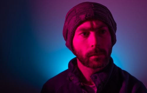 Free Dramatic portrait of a bearded man in a knitted beanie with vibrant lighting. Stock Photo