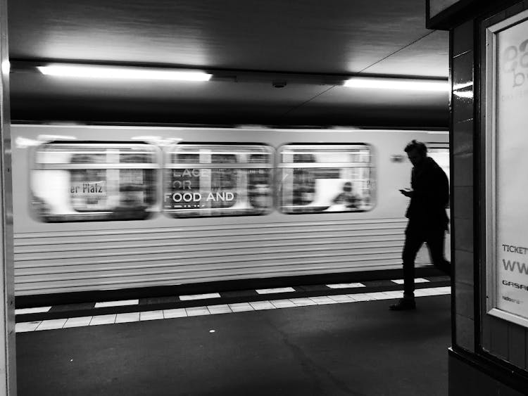 Grayscale Photo Of A Person Near The Train