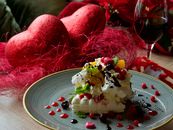 Delicious dessert with fruits and cream served with red wine on a Valentine's themed table.
