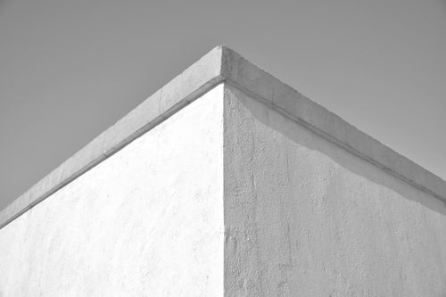Free A minimalist photograph of a concrete wall corner under a clear sky, emphasizing texture and form. Stock Photo